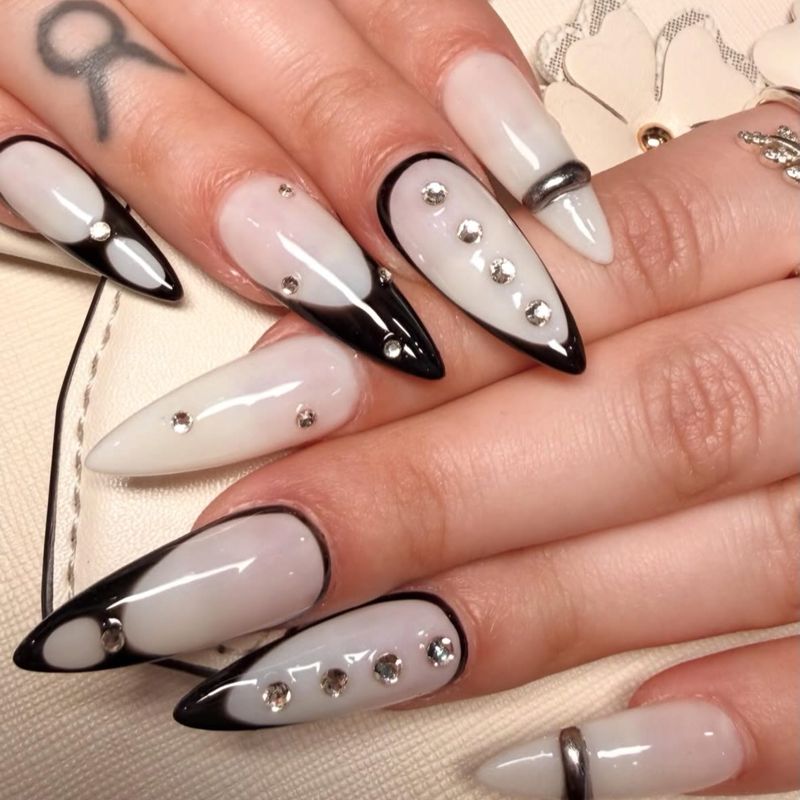 Nude stiletto nails with black outlined French tips and star details by Nini Nail Bar